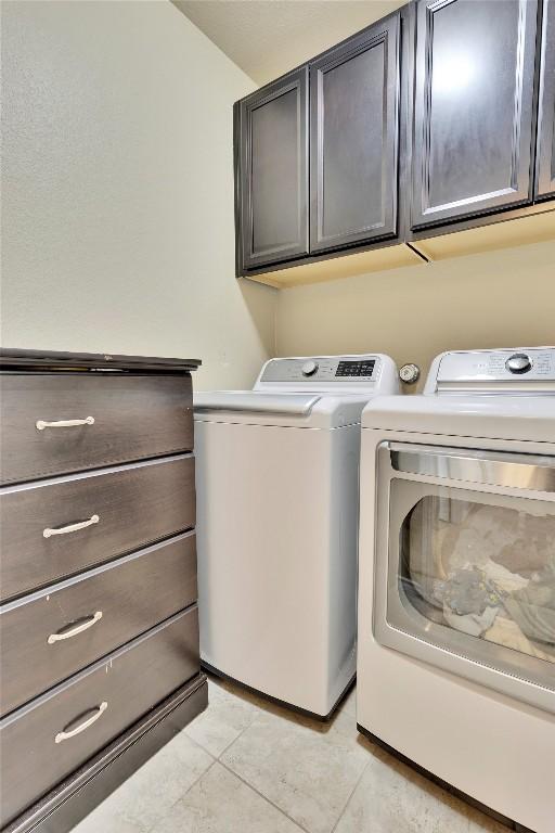 laundry room with light tile patterned flooring, cabinets, and separate washer and dryer