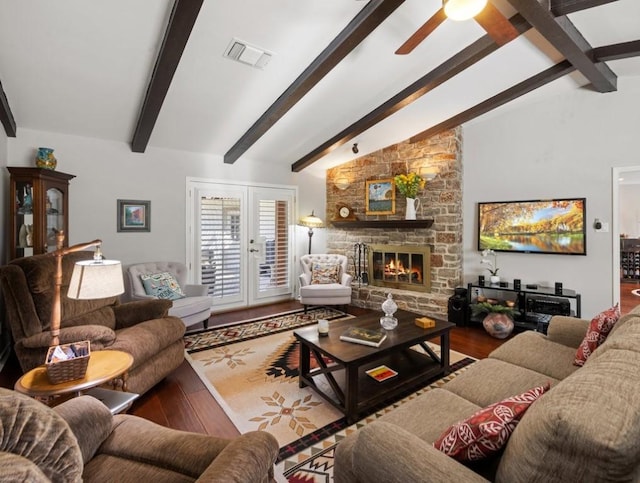 living room with french doors, ceiling fan, wood-type flooring, vaulted ceiling with beams, and a stone fireplace