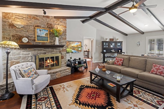 living room with wood-type flooring, lofted ceiling with beams, a stone fireplace, and ceiling fan