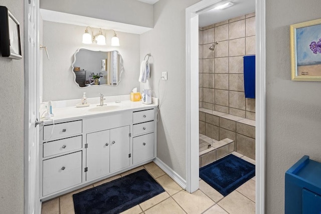 bathroom featuring tile patterned flooring, vanity, and tiled shower