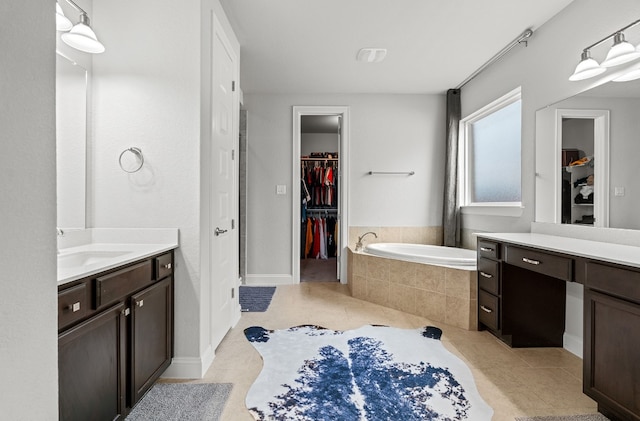 bathroom featuring tile patterned flooring, vanity, and tiled bath