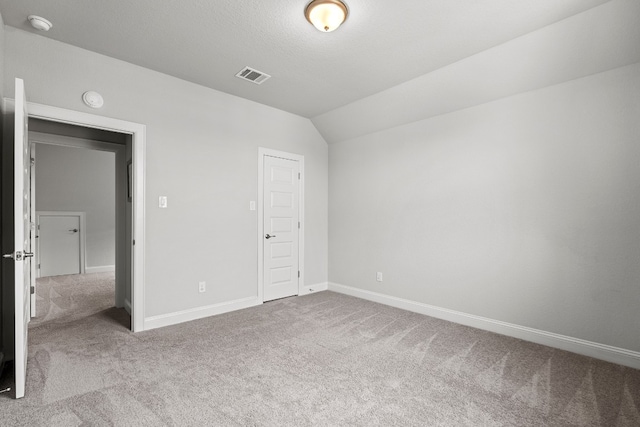 unfurnished bedroom with carpet flooring, lofted ceiling, a textured ceiling, and a closet