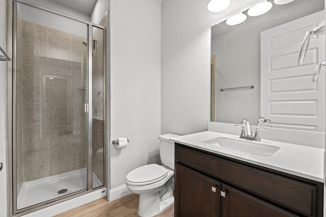 bathroom featuring wood-type flooring, vanity, toilet, and an enclosed shower