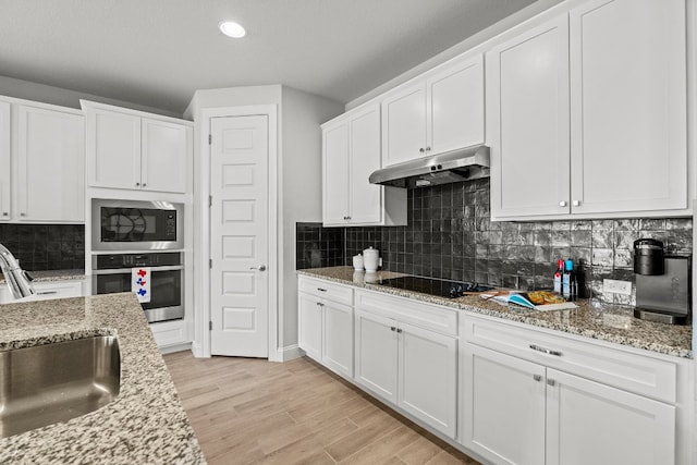 kitchen with oven, white cabinetry, and built in microwave