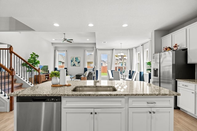 kitchen featuring ceiling fan with notable chandelier, sink, stainless steel appliances, and a kitchen island with sink