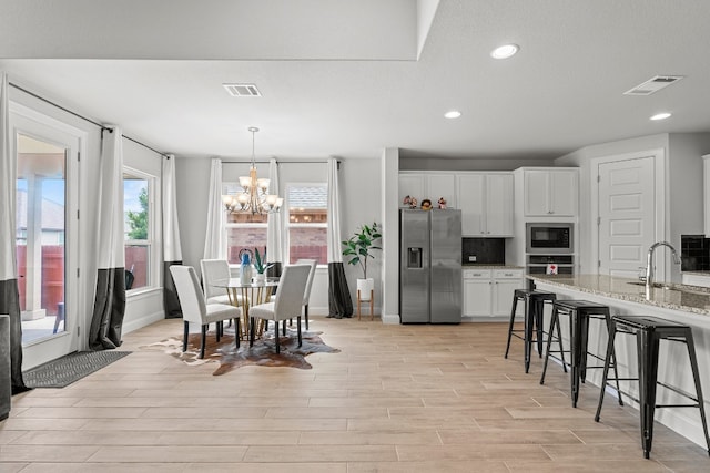 dining area featuring a chandelier, light hardwood / wood-style flooring, and sink