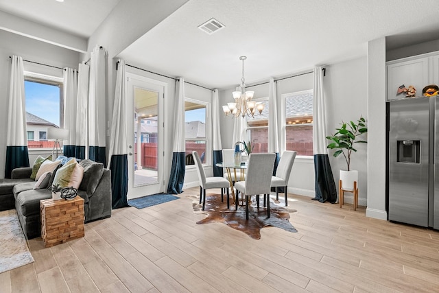 dining room with a wealth of natural light, light wood-type flooring, and a notable chandelier