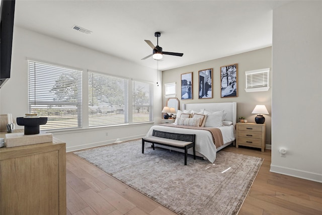 bedroom with light wood-style flooring, a ceiling fan, visible vents, and baseboards