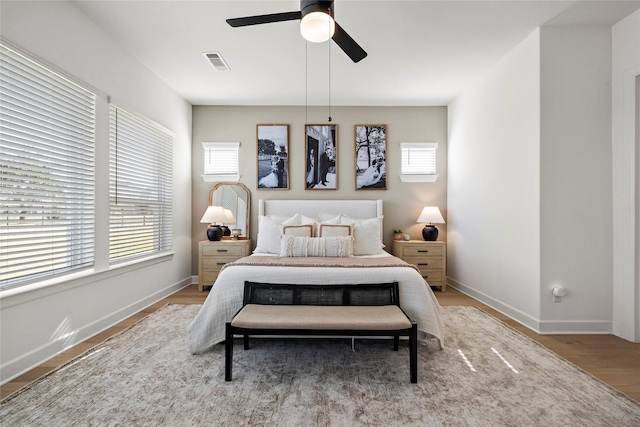 bedroom with light wood-style flooring, a ceiling fan, visible vents, and baseboards