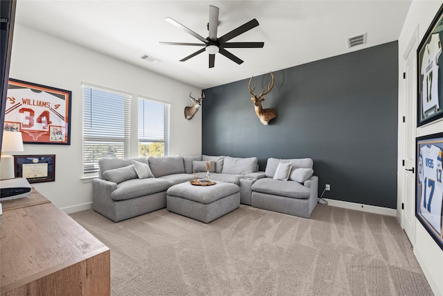 living area with light carpet, ceiling fan, visible vents, and baseboards