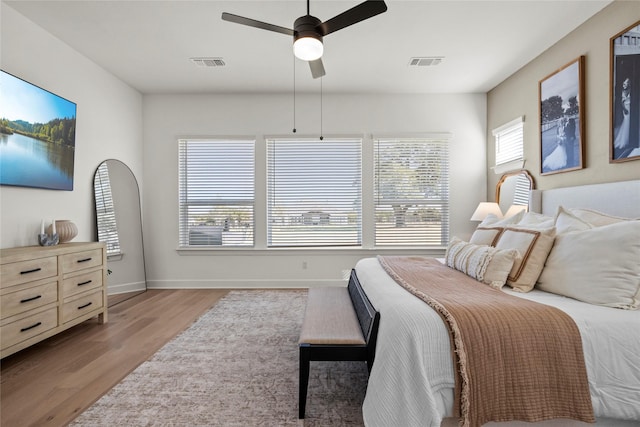 bedroom featuring light wood-style flooring, a ceiling fan, visible vents, and baseboards