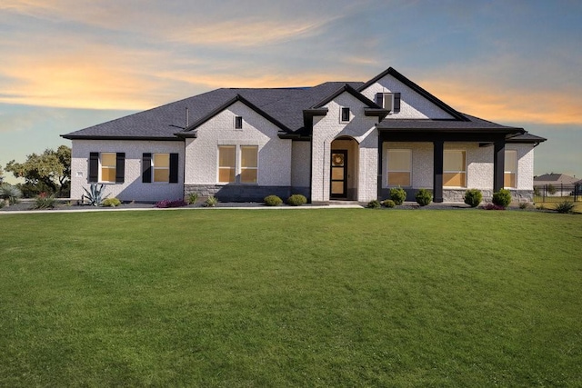 view of front of home with brick siding and a lawn