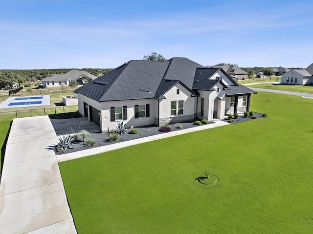 french provincial home featuring a residential view, fence, concrete driveway, and a front yard