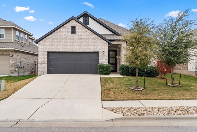 1813 Arapaho Mountain Pass, Leander, TX 78641 - view of front of house with brick siding, a front lawn, concrete driveway, and a garage