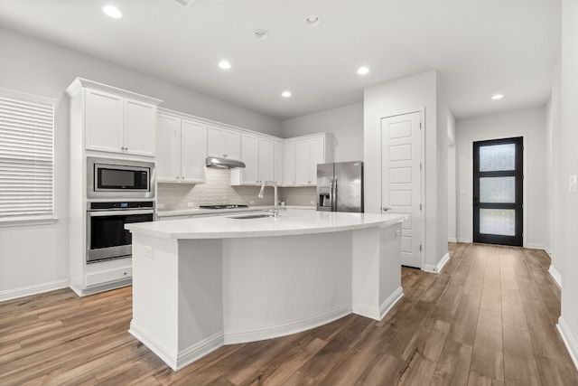 kitchen with appliances with stainless steel finishes, white cabinetry, a kitchen island with sink, and sink