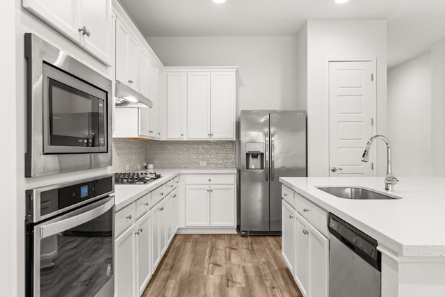 kitchen featuring backsplash, stainless steel appliances, sink, light hardwood / wood-style flooring, and white cabinets