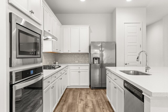 1813 Arapaho Mountain Pass, Leander, TX 78641 - kitchen featuring appliances with stainless steel finishes, light countertops, light wood finished floors, white cabinets, and backsplash