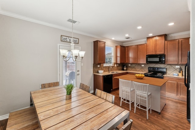 kitchen featuring a kitchen bar, black appliances, a chandelier, a center island, and hanging light fixtures