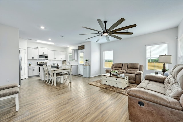 living room with a wealth of natural light, light wood-type flooring, and ceiling fan