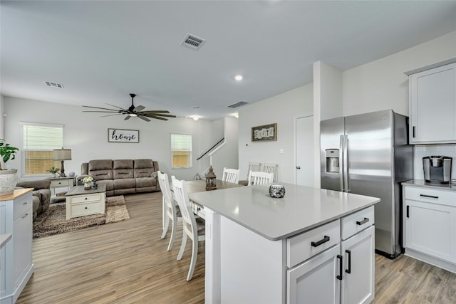 kitchen featuring stainless steel fridge, a center island, light hardwood / wood-style floors, and white cabinetry