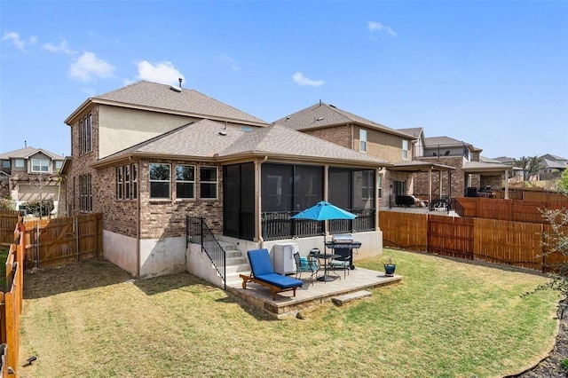 rear view of house with a lawn, a sunroom, and a patio