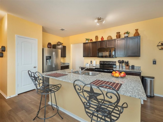 kitchen with a kitchen island with sink, black appliances, sink, dark hardwood / wood-style floors, and dark brown cabinets