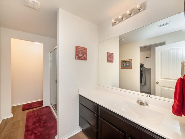 bathroom featuring hardwood / wood-style flooring, vanity, and a shower with door