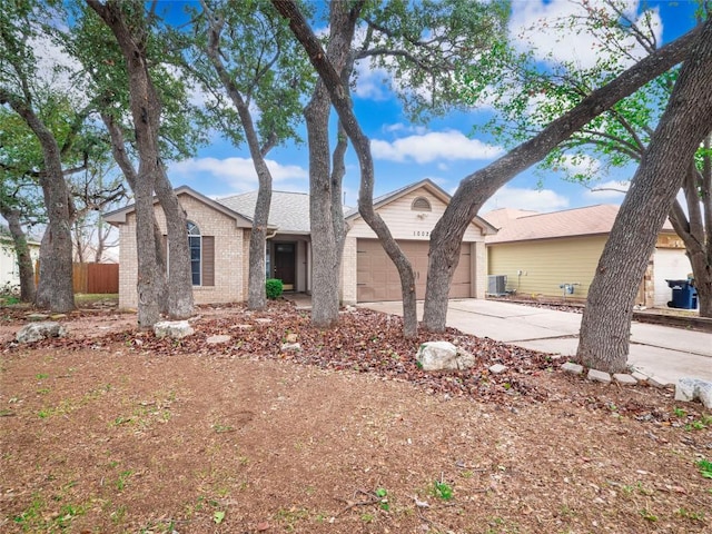 ranch-style home with central air condition unit and a garage