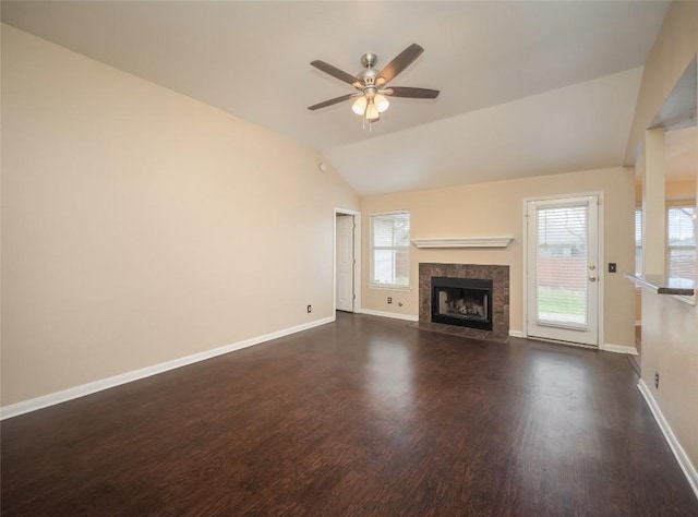 unfurnished living room featuring a healthy amount of sunlight, ceiling fan, lofted ceiling, and a tiled fireplace