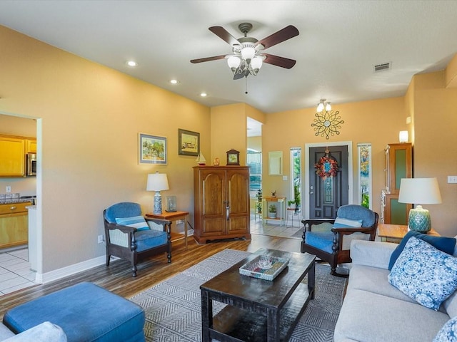 living room with ceiling fan with notable chandelier and light hardwood / wood-style flooring