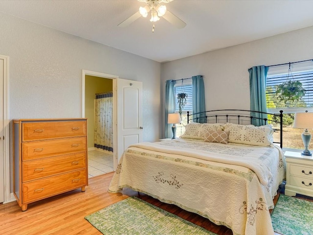 bedroom with ensuite bath, ceiling fan, and light hardwood / wood-style floors