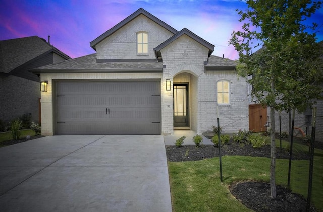 192 Bay Breeze Dr, Kyle, TX 78640 - french provincial home featuring concrete driveway, an attached garage, a front yard, roof with shingles, and brick siding