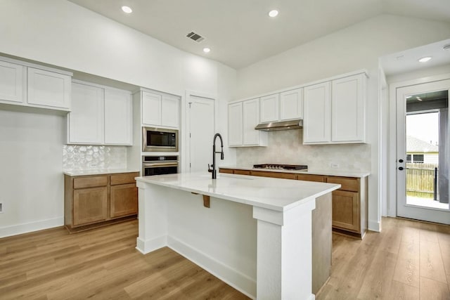 192 Bay Breeze Dr, Kyle, TX 78640 - kitchen with oven, built in microwave, under cabinet range hood, light wood finished floors, and recessed lighting
