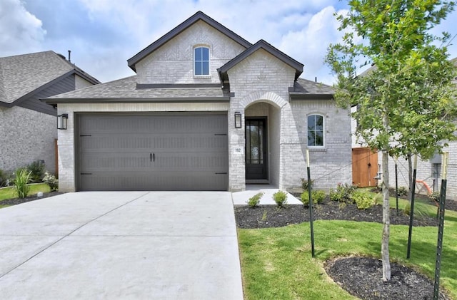 192 Bay Breeze Dr, Kyle, TX 78640 - french country style house with driveway, an attached garage, a front lawn, and brick siding