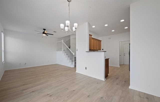 unfurnished living room with ceiling fan with notable chandelier and light wood-type flooring