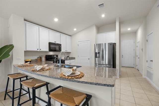 14121 Fallsprings Way, Manor, TX 78653 - kitchen featuring stainless steel fridge, black microwave, a peninsula, light tile patterned floors, and stone countertops