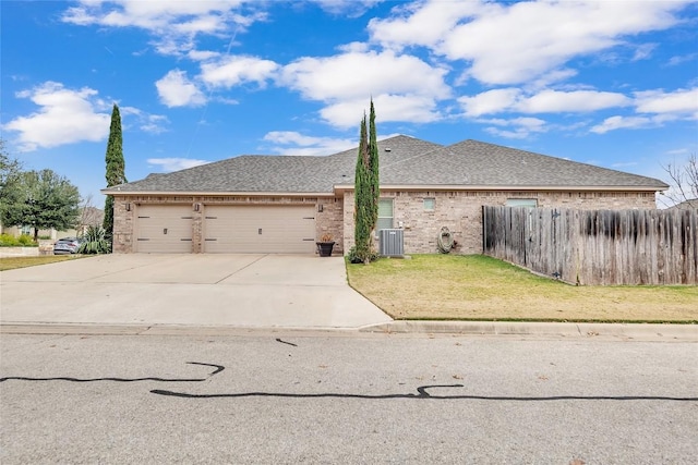 view of front of property featuring a front yard, central AC, and a garage