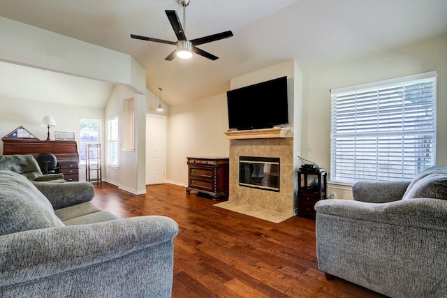 living room with a fireplace, vaulted ceiling, ceiling fan, and dark wood-type flooring