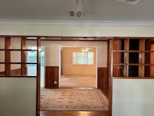 entryway with ceiling fan, crown molding, and wooden walls