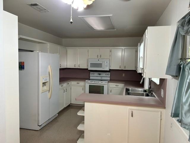 kitchen with kitchen peninsula, white cabinetry, sink, and white appliances