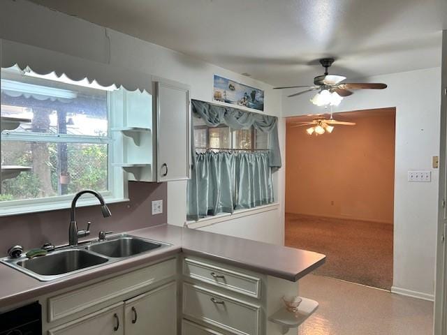 kitchen with light carpet, white cabinets, sink, ceiling fan, and kitchen peninsula