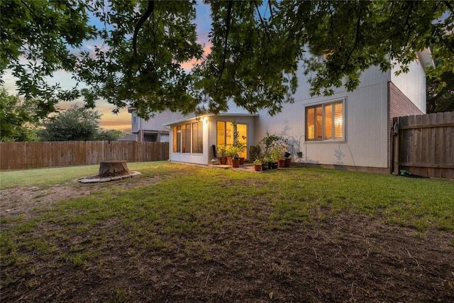 back house at dusk featuring a yard