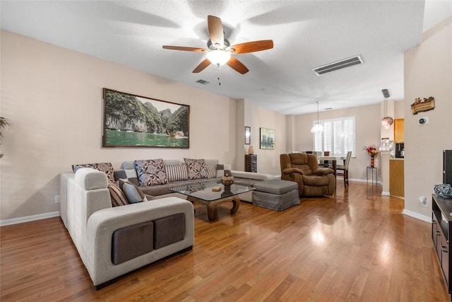 living room featuring a textured ceiling, ceiling fan with notable chandelier, and hardwood / wood-style flooring