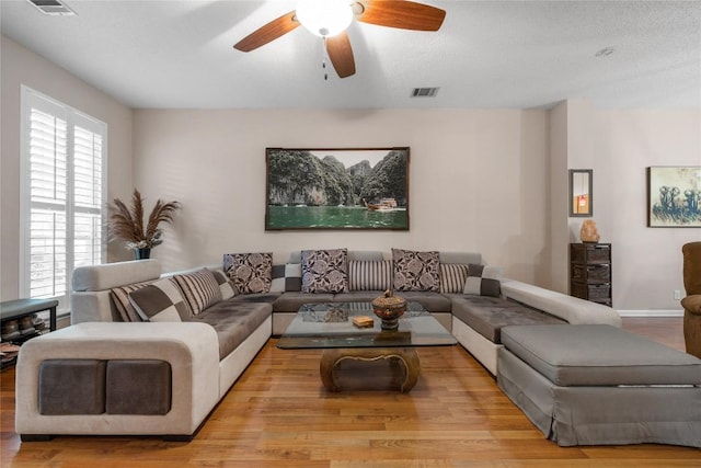 living room featuring ceiling fan, a textured ceiling, and light hardwood / wood-style flooring