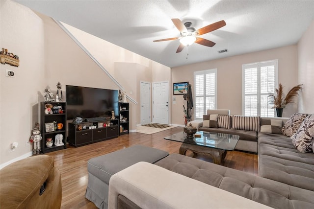 living room featuring ceiling fan, wood-type flooring, and a textured ceiling