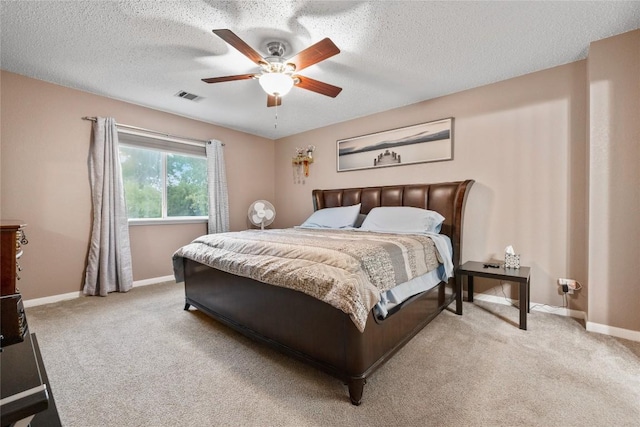 carpeted bedroom featuring ceiling fan and a textured ceiling