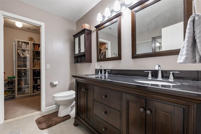 bathroom with tile patterned flooring, vanity, a textured ceiling, and toilet