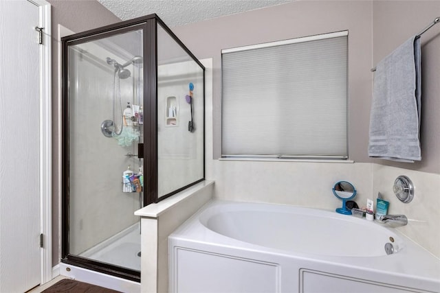 bathroom featuring a textured ceiling and independent shower and bath