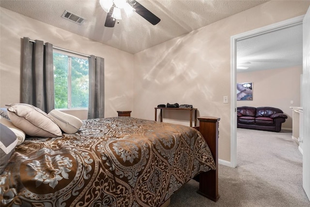 carpeted bedroom featuring ceiling fan and a textured ceiling