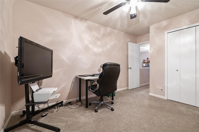 carpeted office space with a textured ceiling and ceiling fan